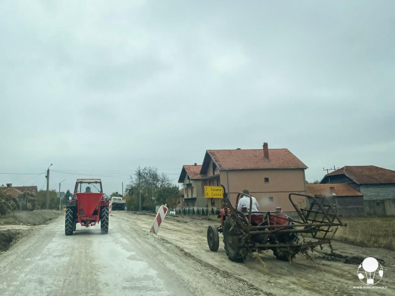 Due trattori che vanno nella stessa direzione su entrambe le corsiesu una strada dissestata in Serbia