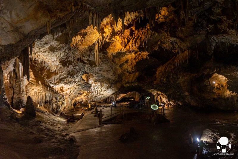 grotta sotterranea illuminata con numerose stalattiti e stalagmiti